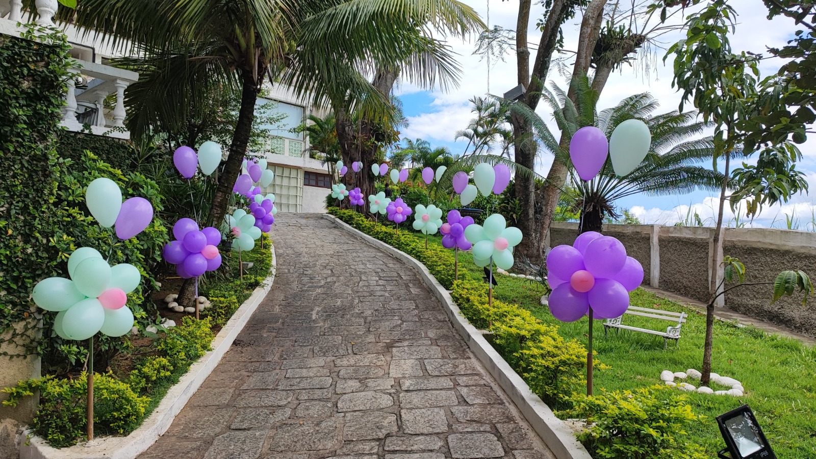 Entrada decorada da Casa Tropical Festas com balões coloridos e palmeiras